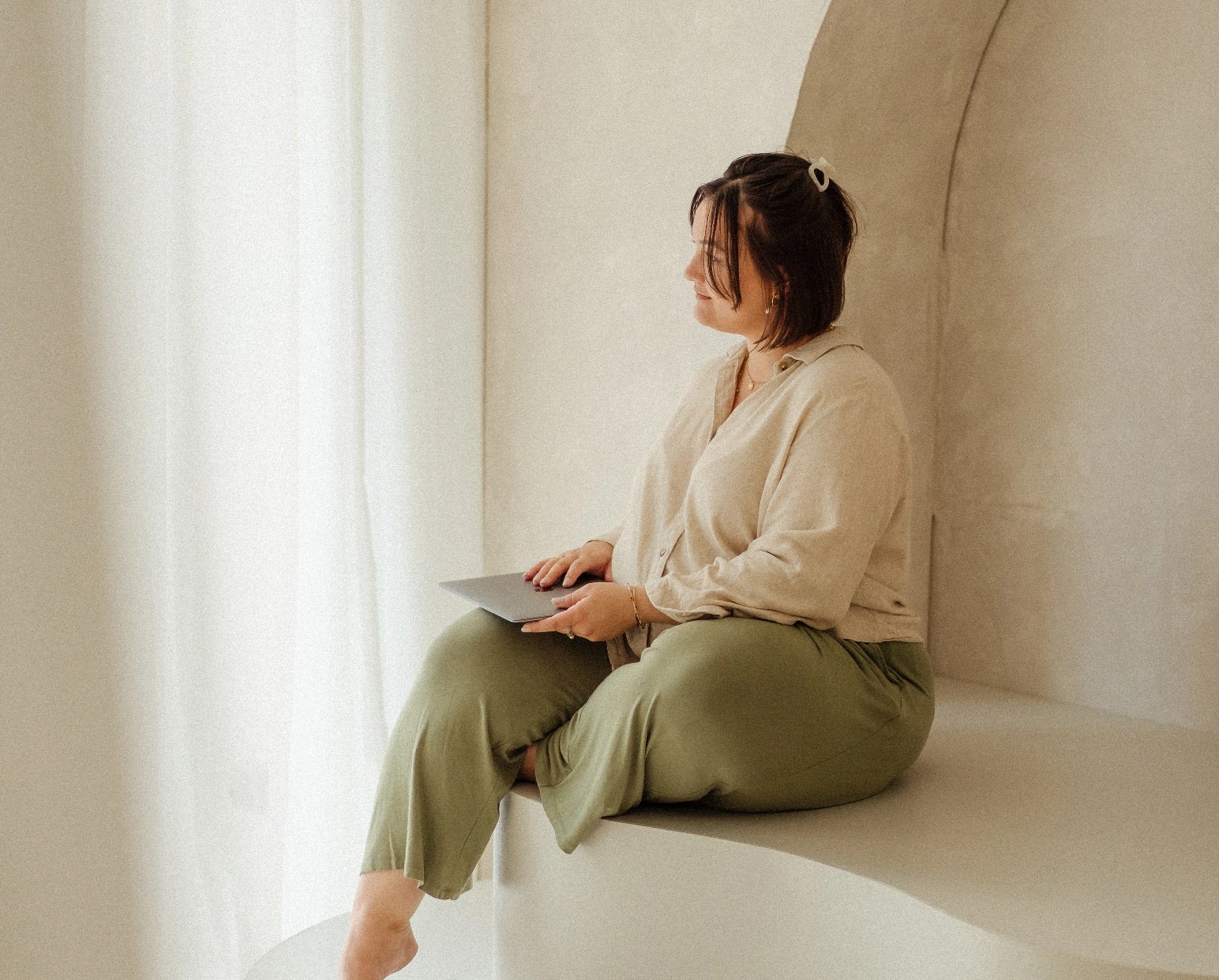 Brand Designerin sitzt mit ihrem Laptop in einem Tageslichtstudio