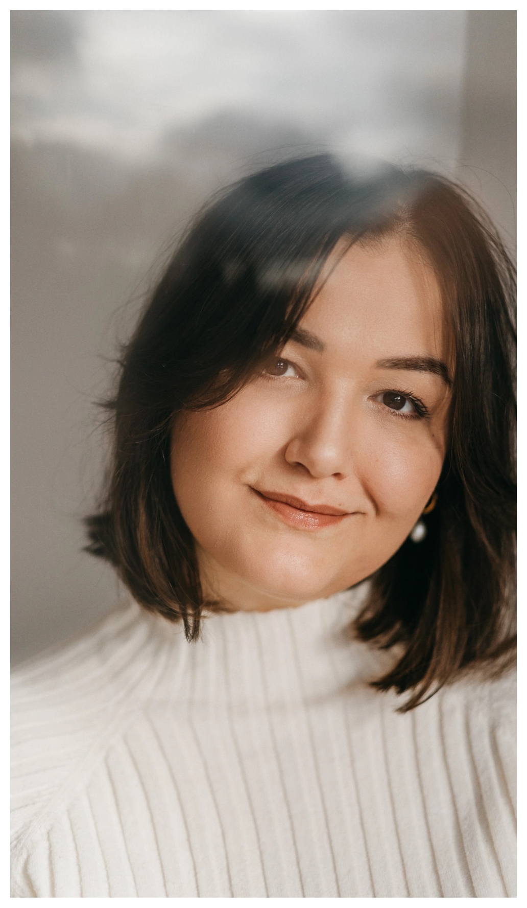 Fotografin sitzt vor einem weißen Vorhang und lächelt